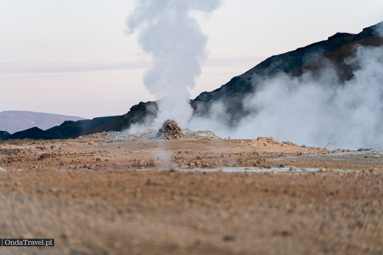 Alta columna de vapor de una fumarola frente a la ladera oscura de Námafjall