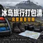 Mochila abierta con ropa impermeable, botas y mapa sobre suelo volcánico de Islandia.
